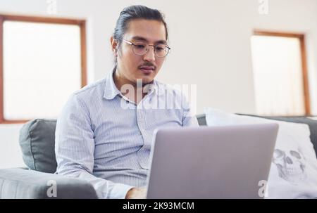 Donnez à votre réussite votre meilleur cliché. Un jeune homme d'affaires utilisant un ordinateur portable sur un canapé dans un bureau moderne. Banque D'Images