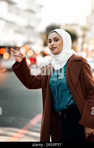 Puis-je obtenir un taxi s'il vous plaît. Une jeune femme attrayante portant un hijab et de louer un taxi dans la ville. Banque D'Images