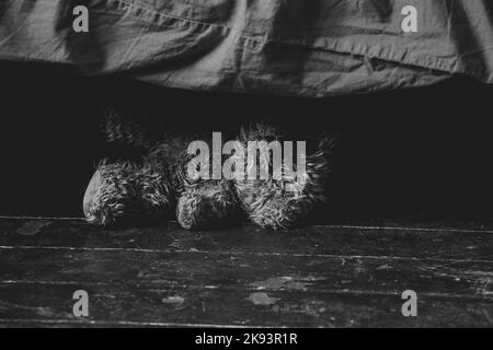 un ours en peluche brun se trouve près du lit sur le sol dans la chambre à la maison, un ours en peluche Banque D'Images
