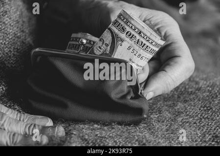 les mains de la vieille femme prennent une facture de dollar d'un portefeuille rouge doux, l'argent dans un portefeuille, la finance Banque D'Images