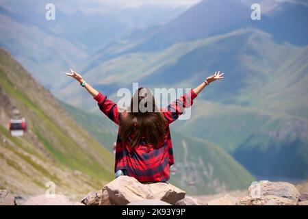 Une heureuse femme touriste sur le sommet de la montagne a levé les mains, jouit de la vue magnifique sur les montagnes. Banque D'Images