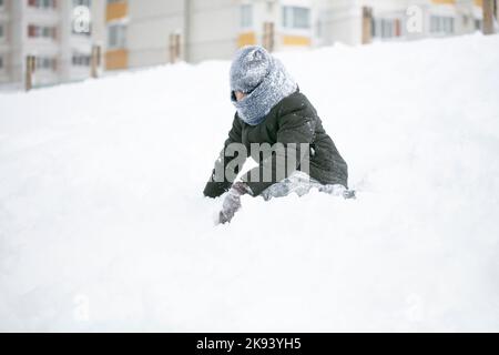 Un garçon bien habillé joue dans la neige un jour d'hiver. Banque D'Images