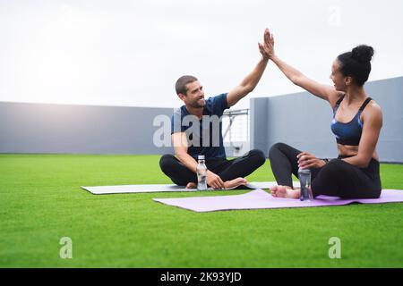 Cette séance a vraiment soulevé leur esprit. Un jeune homme sportif et une femme se donnant un haut cinq tout en faisant de l'exercice à l'extérieur. Banque D'Images