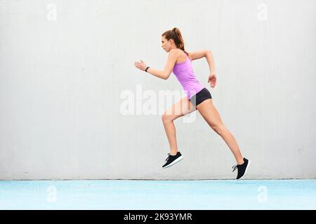 Shes en forme pour la course à venir. Photo en pleine longueur d'une jeune athlète féminine qui court le long de la piste. Banque D'Images