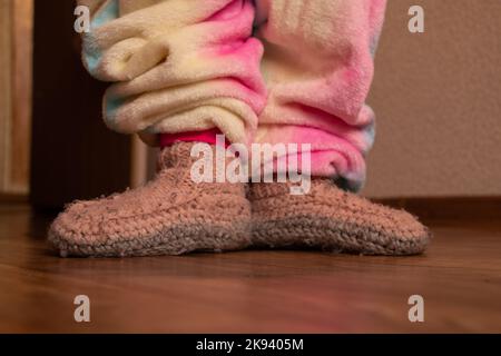 pieds d'enfant en chaussettes chaudes tricotées sur le plancher de la maison en hiver, plancher froid Banque D'Images