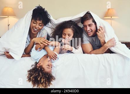 Réveillez-vous en famille. Une famille heureuse se détendant ensemble sous une couverture à la maison. Banque D'Images