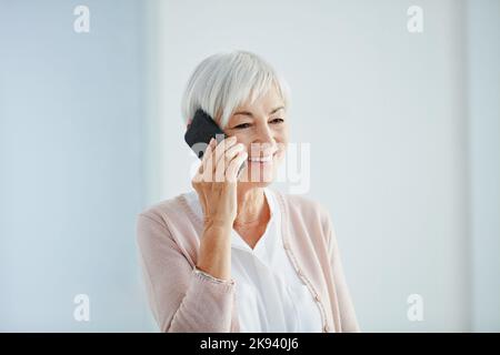 C'est tellement bon d'entendre de vous. Une femme heureuse senior prenant un phonecall en se tenant à l'intérieur dans une maison de retraite. Banque D'Images