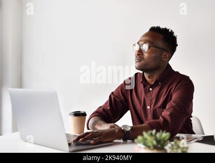 Un beau jeune homme d'affaires qui a l'air contemplatif, assis seul à son bureau, pense à la prochaine meilleure décision. Banque D'Images