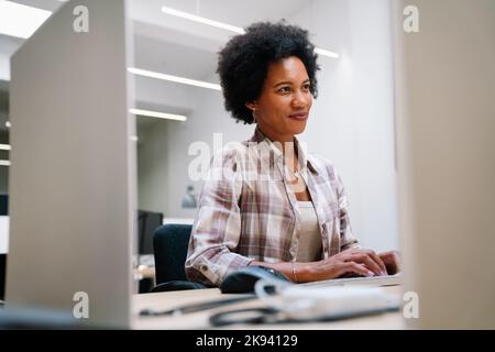 Ouvrier noir concentré d'entreprise analysant les données statistiques de ventes en ligne sur ordinateur Banque D'Images