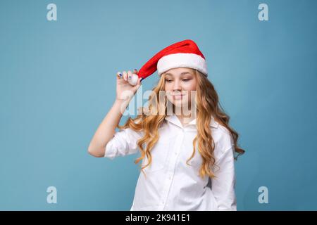 Portrait joyeuse jolie femme dans un chapeau rouge du Père Noël rit, en arrière-plan dans le studio. Belle fille semble heureuse et excitée. Joyeux Noël et bonne année pleine de plaisir. Banque D'Images