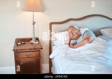 Le meilleur sentiment au monde est de dormir. Un homme âgé dormant seul dans son lit le matin dans une maison de soins infirmiers. Banque D'Images