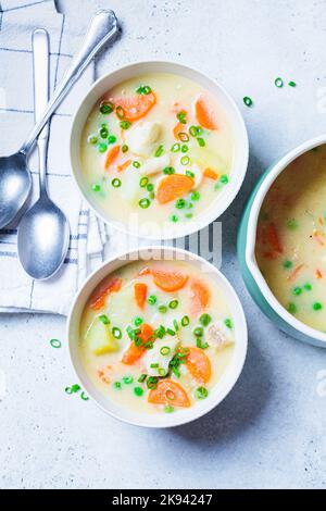 Soupe de morue au poisson avec petits pois, pommes de terre et carottes dans un bol blanc, vue du dessus. Banque D'Images