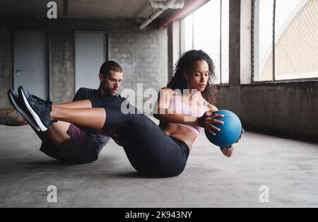 Étaient dans l'oscillation des choses. Photo en longueur d'un jeune couple sportif s'exerçant avec une balle à l'intérieur d'un parking. Banque D'Images