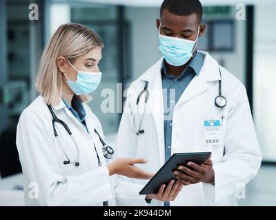 Soins de santé, Covid et médecins vérifiant les données médicales, les dossiers des patients ou les documents d'assurance dans le hall d'accueil de l'hôpital. Masque facial, homme et femme Banque D'Images