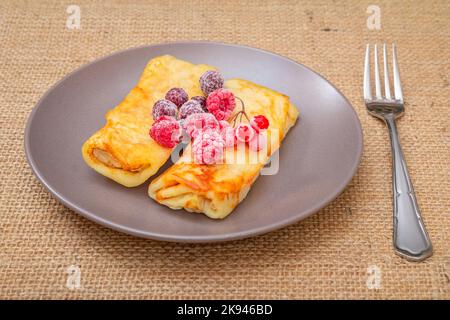 Crêpes faites maison et framboises surgelées sur l'assiette. Banque D'Images