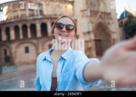 Heureuse femme optimiste touriste dans des lunettes de soleil et des vêtements élégants faisant selfie photo en face de la célèbre cathédrale de Valence ville Banque D'Images