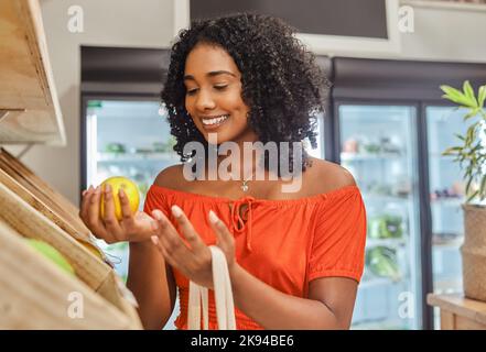 Épicerie, shopping et orange avec une cliente noire dans un magasin de produits pour le consumérisme. Alimentation, supermarché et vente au détail avec une femme consommateur Banque D'Images