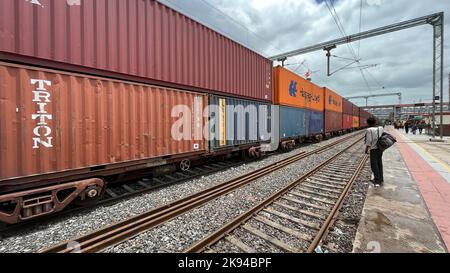 Un train de marchandises à impériale stationnaire avec un passager attendant un train de passagers Banque D'Images