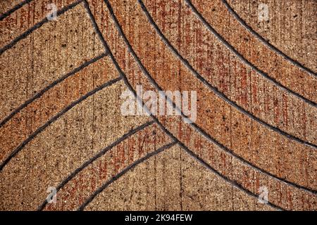 Détail de conception générique de lignes courbes sur une ancienne chaussée dans des tons orange et rouge. Arrière-plan texturé à utiliser comme fond de page ou pour le texte ajouté. Banque D'Images