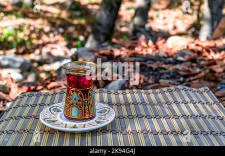 Gros plan sur le thé turc au camping de pique-nique de la forêt. Feuilles sèches d'automne . Thé turc avec verre traditionnel. Banque D'Images