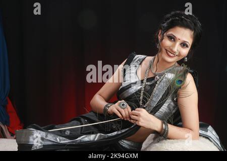 Une belle jeune femme indienne portant une saree en soie noire et argentée et un ensemble de bijoux Banque D'Images