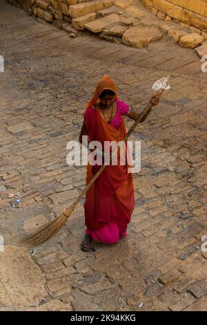Une photo verticale d'une femme balayant les rues du fort d'Or avec un bâton de feu de position Banque D'Images