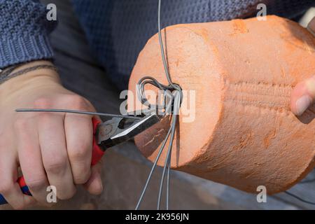 fabrication d'un distributeur pour le matériel de nidification pour les oiseaux ou les écureuils, étape 4: une poignée en forme avec le fil et les extrémités sont coupées, série image 4/5 Banque D'Images