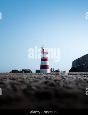 Un cliché vertical d'un petit phare rayé rouge et blanc sur la rive de la mer à Porto, Portugal Banque D'Images