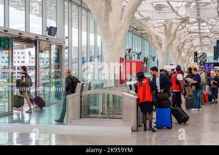 Les voyageurs passent devant des portes d'entrée dans le hall de la gare SNCF de Nantes, en France, conçu par Rudy Ricciotti et doté de piliers en forme d'arbres. Banque D'Images