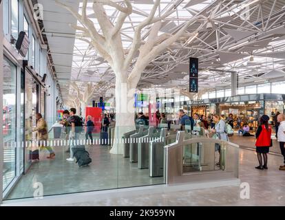 Les voyageurs passent devant des portes d'entrée dans le hall de la gare SNCF de Nantes, en France, conçu par Rudy Ricciotti et doté de piliers en forme d'arbres. Banque D'Images