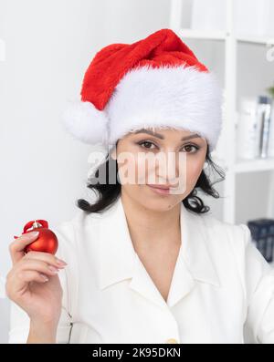 Une jeune femme réussie porte un chapeau de noël sur le bureau de beauté de fond. Portrait professionnel esthéticienne ou directeur et vacances d'hiver Banque D'Images