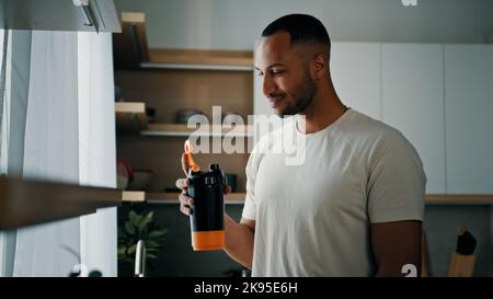 Africain forte santé sport homme sport masculin entraîneur culturiste homme dans la cuisine sourire boire liquide calcium vitamines diététiques suppléments Banque D'Images