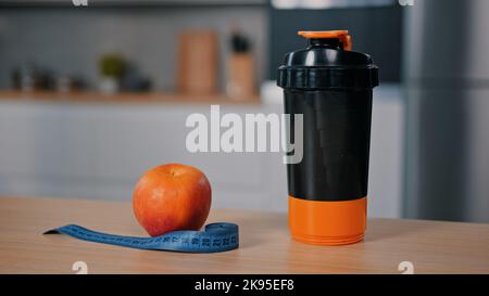 Pomme rouge et mètre ruban sur la table en bois à la maison cuisine bouteille en plastique avec l'eau jus calcium protéines compléments alimentaires vitamines sports nutrition Banque D'Images