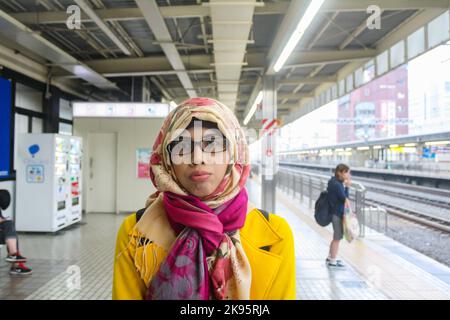 Portrait d'une jeune femme musulmane portant le hijab debout sur la plate-forme de la station de Shizuoka avec fond de bokeh. Expression du visage de canard. Banque D'Images