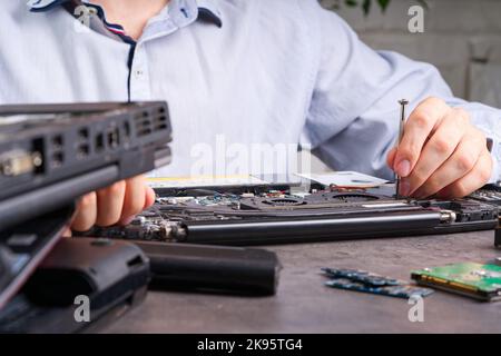 L'homme démonte un ordinateur portable. Concept de réparation et de service informatique. Démontage de l'ordinateur portable dans un atelier de réparation Banque D'Images