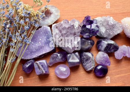 Belles pierres améthystes et druze améthyste avec bouquet de lavande sec sur fond de bois. Amulettes magiques. Banque D'Images