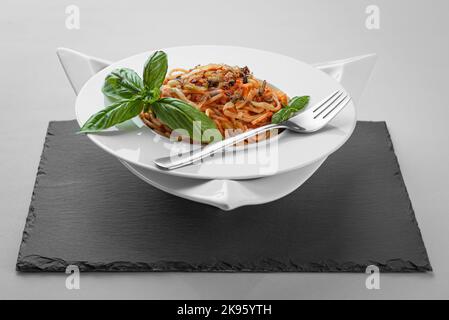 Spaghetti thon pâtes basilic assiette triangle forme ardoise table assez appétissant Banque D'Images
