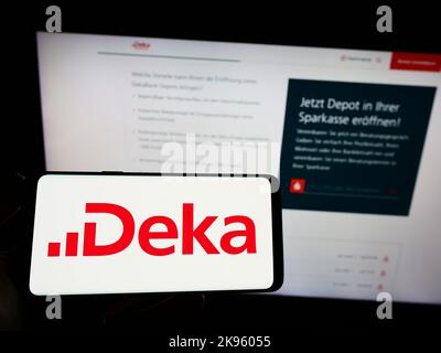 Personne tenant un smartphone avec le logo de DekaBank Deutsche Girozentrale à l'écran devant le site. Mise au point sur l'affichage du téléphone. Banque D'Images