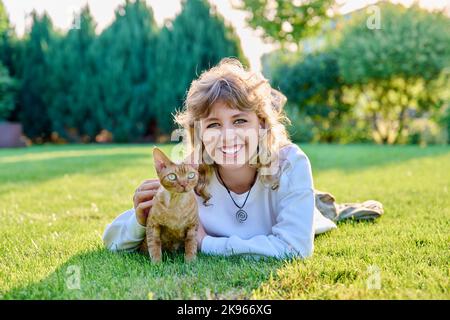 Portrait extérieur d'une adolescente avec chat animal dans les bras allongé sur l'herbe Banque D'Images