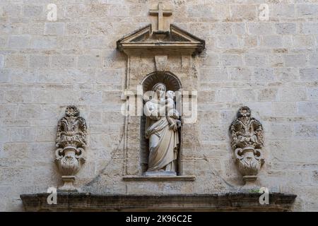 Façade de l'ancien couvent dominicain avec statue en pierre de la Vierge Marie tenant bébé Jésus dans une niche surmontée par croix, Montpellier, France Banque D'Images