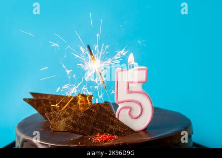 Numéro 5 bougie d'anniversaire brûlant et flambeur avec des étincelles mouche sur le gâteau. Le concept de cinquième anniversaire ou anniversaire de célébration. Beaucoup d'espace de copie. Banque D'Images