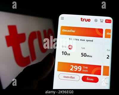 Personne tenant un smartphone avec le site Web de la société thaïlandaise de télécommunications True Corporation à l'écran avec le logo. Concentrez-vous sur le centre de l'écran du téléphone. Banque D'Images