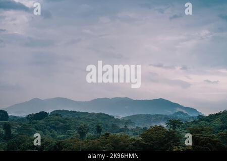 Chaîne de montagnes tropicale avec silhouettes visibles à travers le brouillard coloré du matin. Banque D'Images