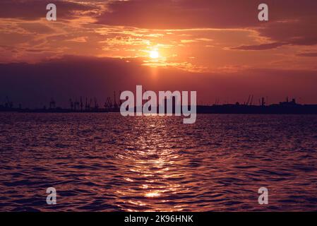 Le magnifique coucher de soleil doré sur la mer Égée à Thessalonique avec silhouettes de grue en arrière-plan Banque D'Images