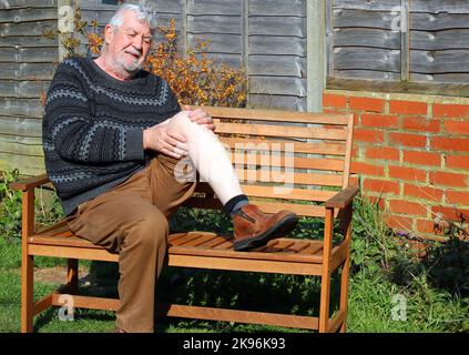 Homme âgé ou âgé souffrant de douleurs à l'arthrite au niveau du genou ou de la jambe. Tenant ses jambes en agonie. Banque D'Images