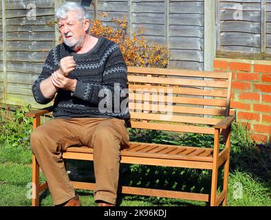 Homme âgé ou âgé tenant son poignet dans la douleur. Agonie causée par l'arthrite ou les blessures de fatigue répétitives. Banque D'Images