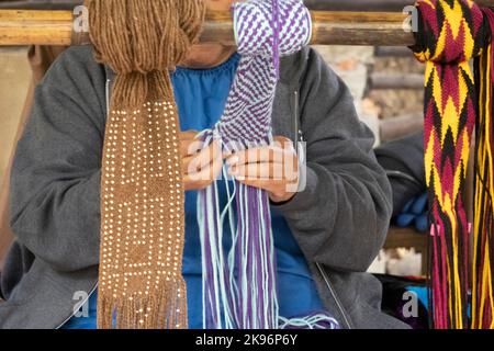 Femme amérindienne tissant à la main une ceinture mauve et blanche. Banque D'Images