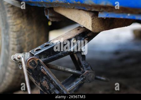 Flou artistique de gros plan d'une voiture soulevée sur un cric en cours de remplacement d'un pneu de roue neuf. Cric de voiture. Levage d'une voiture à l'aide d'une vis de calage. Hors foyer. Banque D'Images