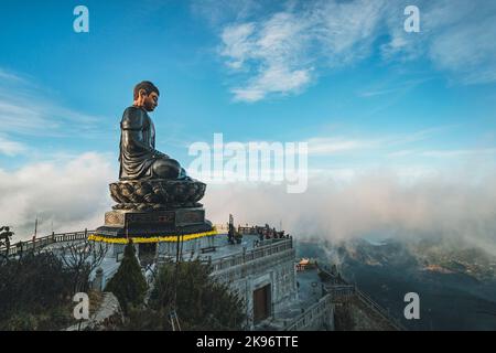 Statue de Bouddha au sommet au coucher du soleil dans les nuages. Statue du Grand Bouddha au sommet de la montagne de Fansipan, Sapa, Lao Cai, Vietnam. Légende Fansipan spectaculaire Banque D'Images