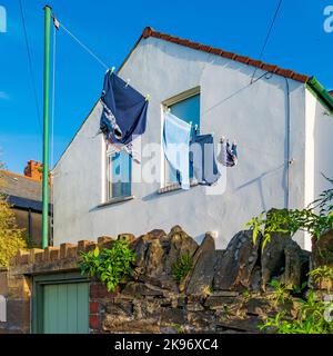 Lavage traîner pour sécher sur une ligne de vêtements à l'extérieur d'une maison mitoyenne à Cardiff, pays de Galles. Chemises colorées, maison et ciel Banque D'Images